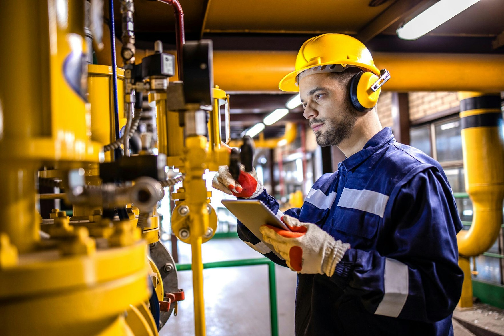 Heating plant technician standing by gas pipes and maintaining temperature